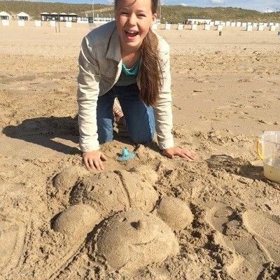 Mädchen hat mit Sandspielzeugen einen Teddy im Sand geformt