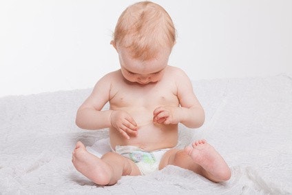 Baby sitzt mit einer Windel auf einer Decke und schaut sich seine Haut an Baby sitzt mit einer Windel auf einer Decke und schaut sich seine Haut an
