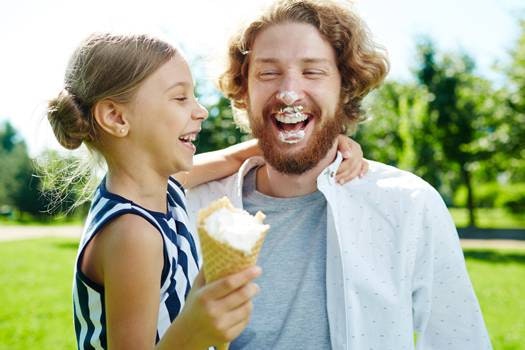 Schulanfang feiern mit Eis Ein Kind bei seinem Vatrer auf dem Arm, mit einem Eis in der Hand.