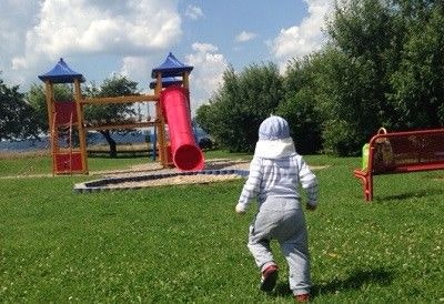 Kleinkind läuft auf einen Abenteuerspielplatz zu.