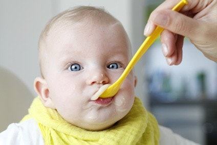 Baby mit einem Löffel Fruchtpüree im Mund Baby mit einem Löffel Fruchtpüree im Mund