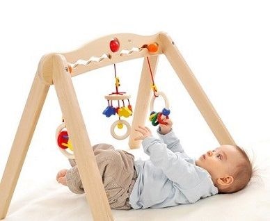 Baby liegt unter einem Spielbogen und Greift nach den hängenden Elementen. Baby liegt unter einem Spielbogen und Greift nach den hängenden Elementen.