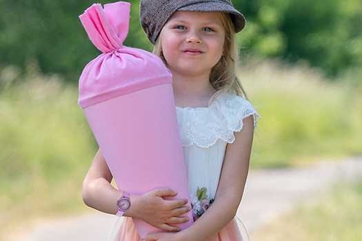 Kind mit Schultüte zum Schulstart Ein Mädchen in der Natur mit einer rosa Schultüte in den Armen