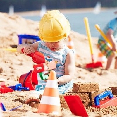 Junge mit Bauarbeiterhelm im Sand Bauarbeiter spielen im Sand