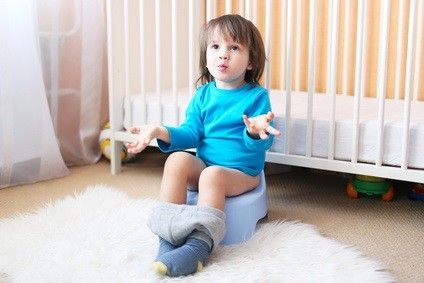 Kind sitzt in seinem Zimmer auf dem Töpfchen und zeigt seine leeren Hände