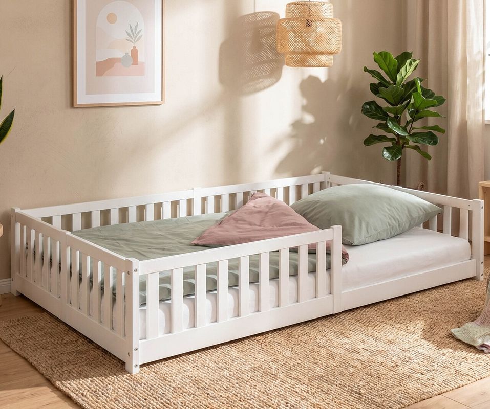 Ein Bodenbett in weiß, mit Rausfallschutz, in einem schlicht eingerichtetem Kinderzimmer