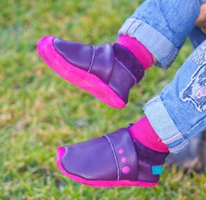 Lieblinge Krabbelschuhe Kinderfüße, die Leder-Krabbelschuhe anhaben, auf Rasen