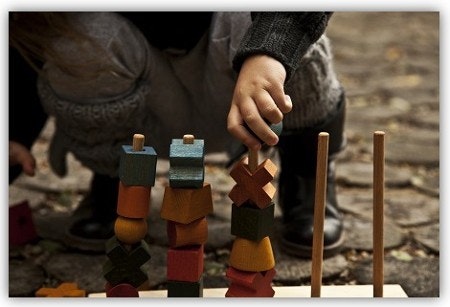 Steckspiel Wooden Story Ein Kind mit einem Steckspiel draußen.