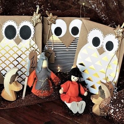 Adventskalender nachhaltig befüllt Adventskalender aus braunen Papiertüten im Eulen-Design, davor stehen Figuren aus Holz: zwei Engel, ein Ritter und eine normale Spielfigur