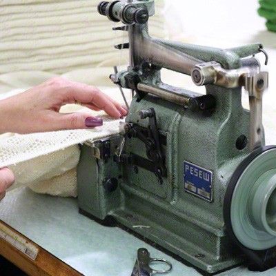 Eine Babydecke wird per Hand an einer Nähmaschine vernäht.