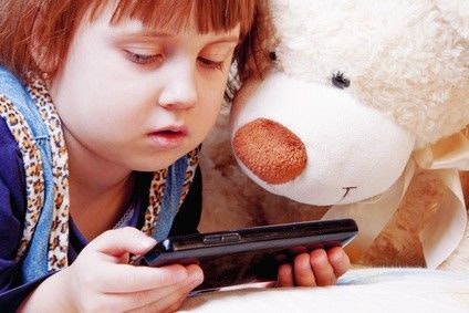 Kleinkind schaut mir seinem Teddy gebannt auf einen Handy-Bildschirm