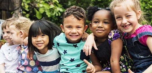 Kinder mit verschiedenen Wurzeln stehen Arm in Arm in einer Reihe.