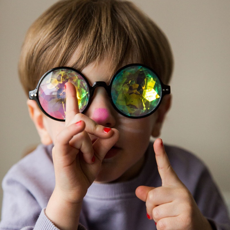 Accessoires und Schminke verleihen jedem Kostüm den perfekten Schliff! Junge mit bunter Brille, eine rosa geschminkte Nase und roten Nagellack