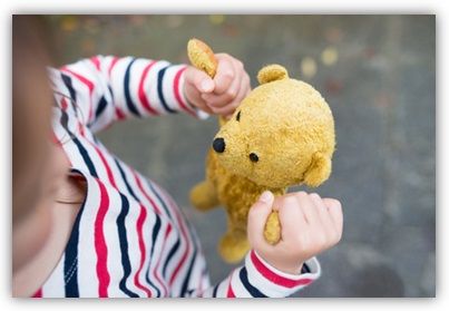 Ein Kind mit einem Teddybär in den Händen.