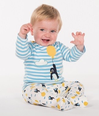 Baby in Strampler mit Fuß mit Pinguin-Muster drauf Baby in Strampler mit Fuß mit Pinguin-Muster drauf