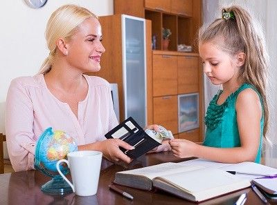 Mutter gibt ihrer Tochter etwas Geld aus ihrem Portemonnaie.