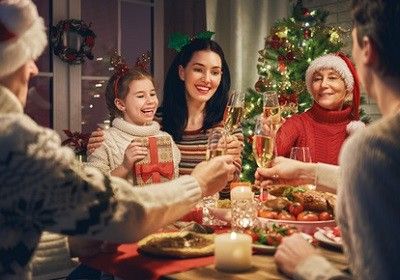 Familie sitzt beim Weihnachtsessen und stößt an.