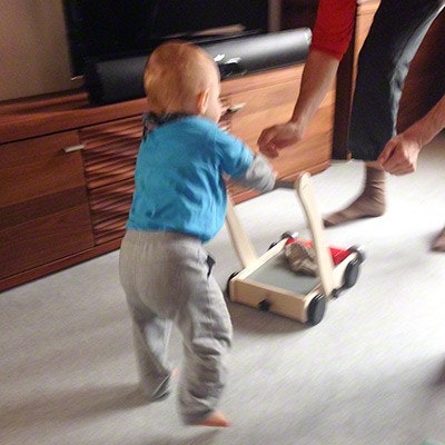 Baby läuft mithilfe eines Lauflernwagens von PlanToys in die Arme seiner Mutter. Baby läuft mithilfe eines Lauflernwagens von PlanToys in die Arme seiner Mutter.
