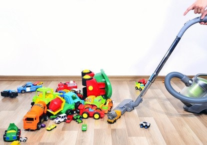 Es liegen so viele Spielzeugautos in verschiedenen Formen, Farben und Größen auf dem Boden, dass die Mutter mit dem Staubsauger nicht durchkommt. Es liegen so viele Spielzeugautos in verschiedenen Formen, Farben und Größen auf dem Boden, dass die Mutter mit dem Staubsauger nicht durchkommt.