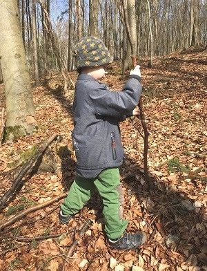 Spielen im Wald Ein Kind im Wald mit einem Stock in der Hand