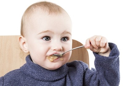 Baby isst mit einem Löffel Breikost. Baby isst mit einem Löffel Breikost.