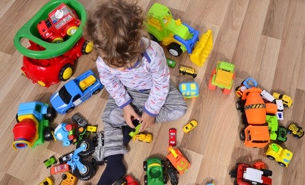 Kind sitzt zwischen vielen Spielzeugautos auf dem Boden Kind sitzt zwischen vielen Spielzeugautos auf dem Boden