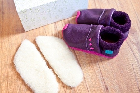 Lieblinge Krabbelschuhe und Einlegesohlen aus Lammfell Ein Paar Leder-Krabbelschuhe, daneben ein Paar Lammfell Einlegesohlen