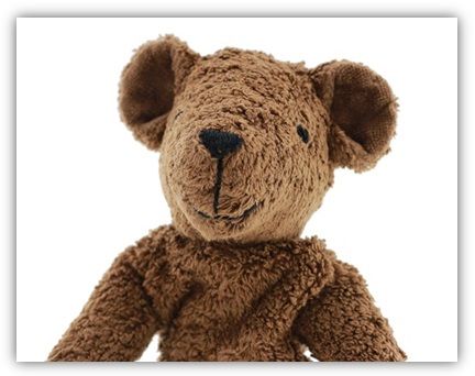 Man sieht den Kopf und den Oberkörper eines dunkelbraunen Teddybäres. Augen und Nase, Mund sind aufgenäht.