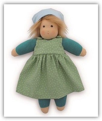 Eine Stoffpuppe mit dezenten, aufgemalten Gesicht. Sie hat Haare aus Wolle, ein Kopftuch, und ein grünes Kleid an.