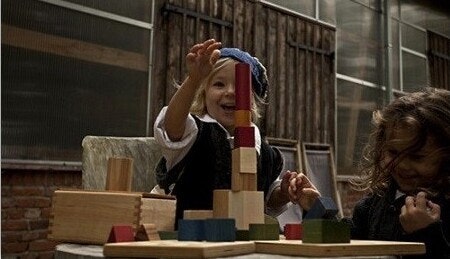 Türme bauen mit Holzbausteinen von Wooden Story Zwei Kinder sitzen an einem Tisch und bauen einen Turm mit bunten Holzbausteinen