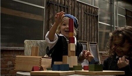 Zwei Kinder sitzen an einem Tisch und bauen einen Turm mit bunten Holzbausteinen