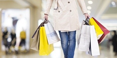 Frau beim Shoppen trägt 8 Tüten durchs Einkaufcenter Frau beim Shoppen trägt 8 Tüten durchs Einkaufcenter