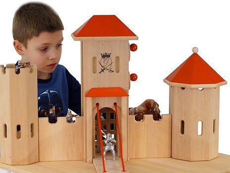Junge spielt mit großer Ritterburg aus Holz