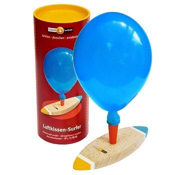 Ein kleines Holzboot mit einem ausgeblasenem Luftballon auf dem Mast.