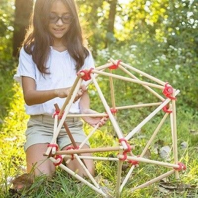 Stick-lets für kreatives Bauen Ein Kind im Wald mit einer geometrischen Figur aus Stäben und Stick-lets gebaut.