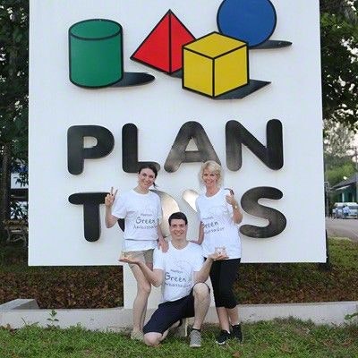 Backgroundcheck PlanToys Fabrik in Trang - Thailand Inna und Denver Mielke mit einer Mitarbeiterin vor dem großen PlanToys-Schild