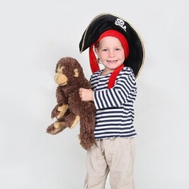 Kind im einfachen Piratenkostüm: gestreifter Pullover, Piratenhut, Affe in der Hand