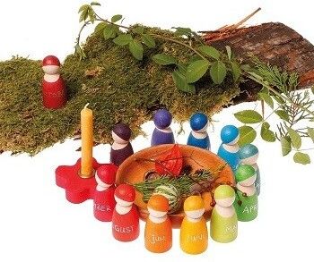 Grimms Regenbogenfreunde mit jeweils einem Monat draufgeschrieben. Dekoriert mit Ästen und Moos und einer Kerze