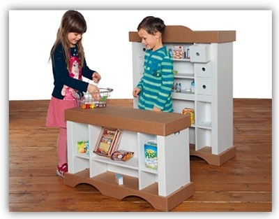 Zwei Kinder spielen im Kaufladen aus Pappkarton Zwei Kinder spielen im Kaufladen aus Pappkarton