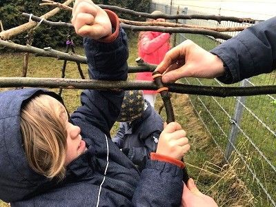 Kinder bauen ein Gerüst aus Stick-lets und Ästen