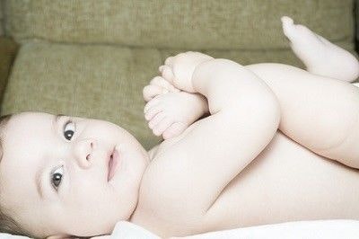 Baby liegt auf dem Rücken und schaut zur Seite in die Kamera