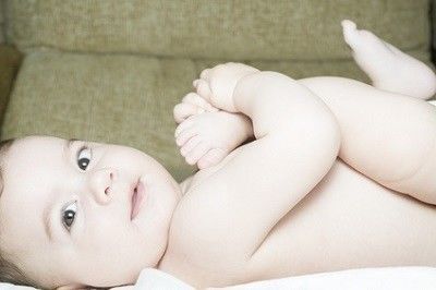 Baby liegt auf dem Rücken und schaut zur Seite in die Kamera