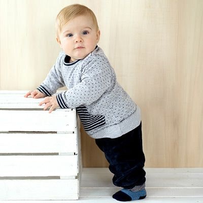Ein Baby hält sich im Stehen an einer Kiste fest. Ein Baby hält sich im Stehen an einer Kiste fest.