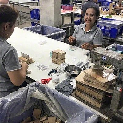 Sozialer Standard und hohe Mitarbeiterzufriedenheit bei PlanToys in Thailand Mitarbeiterin sitzt an ihrem Arbeitsplatz und lächelt in die Kamera