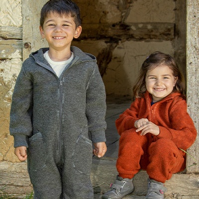 Mädchen und Junge sind draußen und tragen Wollwalk-Overalls Mädchen und Junge sind draußen und tragen Wollwalk-Overalls