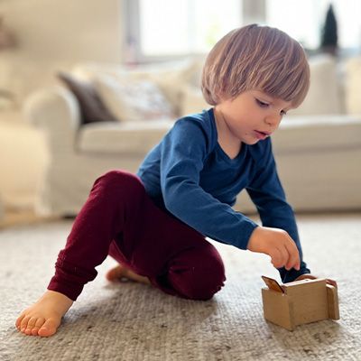 Junge trägt Wollkleidung und spielt auf dem Boden