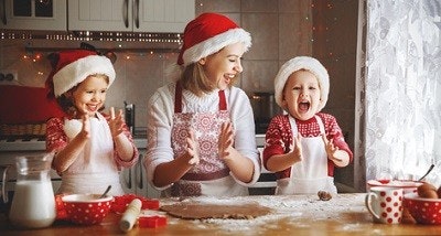 Mutter hat mit ihren zwei Kindern Spaß beim Plätzchenbacken. Alle drei tragen Weihnachtsmützen. Mutter hat mit ihren zwei Kindern Spaß beim Plätzchenbacken. Alle drei tragen Weihnachtsmützen.