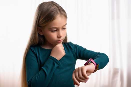 Mädchen schaut nachdenklich auf ihre erste Kinderuhr Mädchen schaut nachdenklich auf ihre erste Kinderuhr
