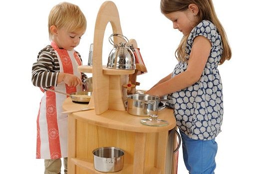 Zwei Geschwister spielen an der doppelseitigen Spielküche von Glückskäfer